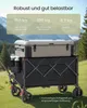 A foldable wagon with a cooler on top, set in a grassy outdoor environment with trees and mountains in the background. Produktbild-Vorschau