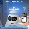 A person is holding a smartphone next to a white alarm clock with a digital display and blue LED lighting. Produktbild-Vorschau