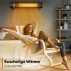 A woman is relaxing in a rocking chair in front of a bed, with an infrared heater mounted on the wall above. Náhľad obrázku produktu
