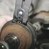 A close-up view of a tool gripping a part of a car's axle assembly. Produktbild-Vorschau