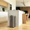 A modern kitchen with a stainless steel trash can in the foreground, next to a marble island and a wooden counter. Anteprima dell’immagine prodotto
