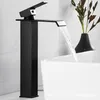 A black waterfall faucet is shown in a bathroom setting, with water flowing into a white sink. A decorative plant in a black vase is visible in the background. Produktbild-Vorschau
