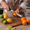 A person is zesting an orange with a Microplane zester over a cutting board with other citrus fruits. Anteprima dell’immagine prodotto