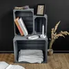 A still life arrangement of wooden crates used for storage, decorated with books, a candle, dried flowers, and a framed picture. Produktbild-Vorschau