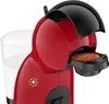 A close-up shot of a red and black coffee machine with a capsule inserted. Anteprima dell’immagine prodotto