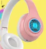 Close-up of pink and white wireless headphones with a blue LED light-up circuit board design on the ear cup. Produktbild-Vorschau