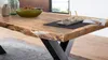 A close-up view of a wooden dining table with a live edge, set in a dining room environment. Produktbild-Vorschau
