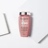A pink bottle of Kérastase shampoo is placed on a white surface with geometric folds. Anteprima dell’immagine prodotto