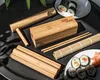 A collection of bamboo sushi-making tools and finished sushi rolls arranged on a dark surface. Náhľad obrázku produktu