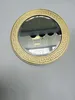 A round mirror with a gold and white decorative frame is mounted on a light gray wall. Náhľad obrázku produktu
