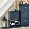 A blue shoe cabinet with shoes inside, placed next to a staircase and a lantern. Náhľad obrázku produktu