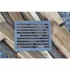A cast iron grate is placed on a pile of firewood. Voir les images du produit
