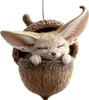 A cute fennec fox is sleeping inside a knitted acorn ornament. Produktbild-Vorschau
