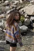A woman stands in a stream with rocks and flowing water. Produktbild-Vorschau