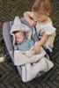 A baby sleeping in a car seat, with a toddler looking at them. Anteprima dell’immagine prodotto