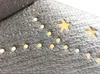 A close-up view of a silver textured surface decorated with gold stars and dots, resembling a festive decoration. Anteprima dell’immagine prodotto