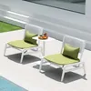 Two white lounge chairs with green cushions and pillows are placed on a patio next to a pool. A small white side table with a fruit platter and drinks sits between the chairs. Anteprima dell’immagine prodotto