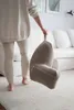 A person is holding a reading pillow in a living room with a sofa in the background. Náhled obrázku produktu
