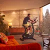 A man is exercising on an Adidas exercise bike in a modern living room with a sofa and plants. Produktbild-Vorschau