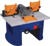 A woodworking router table with orange safety guards and a clear dust collection shroud. Produktbild-Vorschau