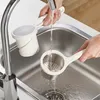 Hands washing a potato masher under a faucet in a kitchen sink. Anteprima dell’immagine prodotto
