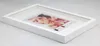 A white wooden 3D object frame with a picture of a woman inside, placed on a light gray surface. Produktbild-Vorschau