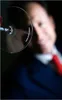 A close-up of a wine glass with a person blurred in the background. Náhled obrázku produktu