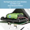 Close-up view of a battery compartment with a green battery pack inside, showing instructions on how to remove it. Produktbild-Vorschau