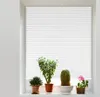 Four potted plants are displayed on a windowsill in front of white blinds. Voir les images du produit