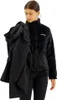 A woman is holding a black jacket over her shoulder while wearing another black jacket. Produktbild-Vorschau