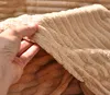A hand is holding and bunching up a soft, textured fabric. Produktbild-Vorschau