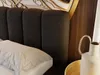A close-up view of a bed with a dark bouclé headboard and a white pillow. Produktbild-Vorschau