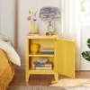 A yellow nightstand with an open door, placed next to a bed. The nightstand has decorative items on top and inside. Produktbild-Vorschau