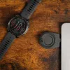 A smartwatch and a charging adapter are placed on a wooden surface. Produktbild-Vorschau