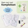 A sewing kit for making a stuffed alpaca, with fabric pieces, stuffing, buttons, and instructions. Produktbild-Vorschau