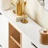 A close-up view of a white cabinet with a wooden interior shelf, decorated with gold accessories. Náhľad obrázku produktu