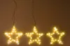 Three illuminated star-shaped lights hanging against a brown background. Produktbild-Vorschau