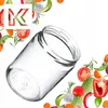 A glass jar is shown tilted on a white background, surrounded by various fresh vegetables and herbs. Voir les images du produit