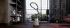 A vacuum cleaner is placed in a modern living room with large windows overlooking a city. Produktbild-Vorschau