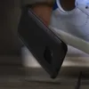 A black smartphone case is falling towards the ground, with a white sneaker in the background. Podgląd zdjęcia produktu
