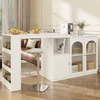 A white bar table with a sideboard and glass cabinet doors, set in a living room with a brown leather sofa and wooden flooring. Produktbild-Vorschau