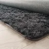 A close-up view of a fluffy gray rug with a textured backing, lying on a light-colored wooden floor. Anteprima dell’immagine prodotto