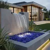 Blaue Glasbrocken im Auffangbecken eines modernen Gartenwasserfalls Produktbild-Vorschau