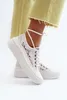 A close-up shot of a person's feet wearing white lace sneakers with ankle straps. Voir les images du produit