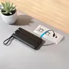 A black power bank with integrated cables is shown plugged into a multi-socket power strip, with a small potted plant in the background. Anteprima dell’immagine prodotto