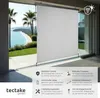 A white retractable awning is shown extended in front of a large glass sliding door, with a scenic view of a beach and ocean visible through the glass. Náhled obrázku produktu