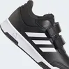 A close-up view of a black Adidas shoe with white stripes and velcro straps. Podgląd zdjęcia produktu