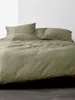 A neatly made bed with green bedding. Produktbild-Vorschau