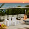 A table setting with candles and wine glasses on a deck overlooking the ocean at sunset. Produktbild-Vorschau