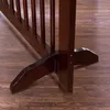 A close-up view of the base of a wooden stair gate, showing its support feet and the wooden floor it rests on. Podgląd zdjęcia produktu